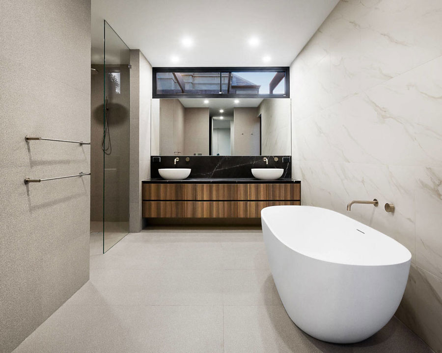 In deze moderne luxe badkamer is een grote badkamermeubel op maat gemaakt met dubbele wastafels.