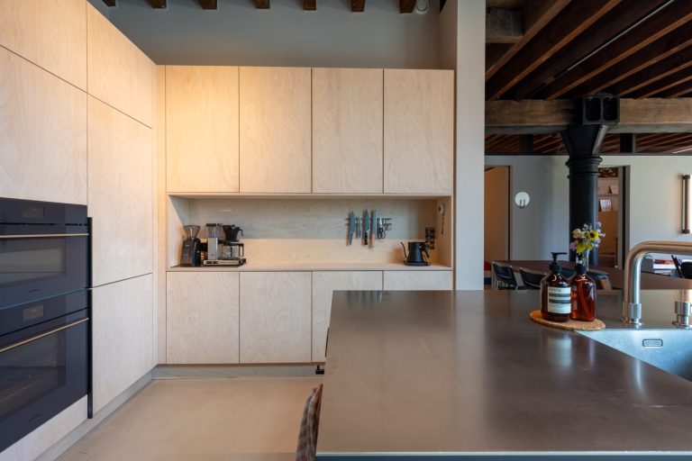 Een stoere moderne keuken met berken multiplex en een zwart kookeiland