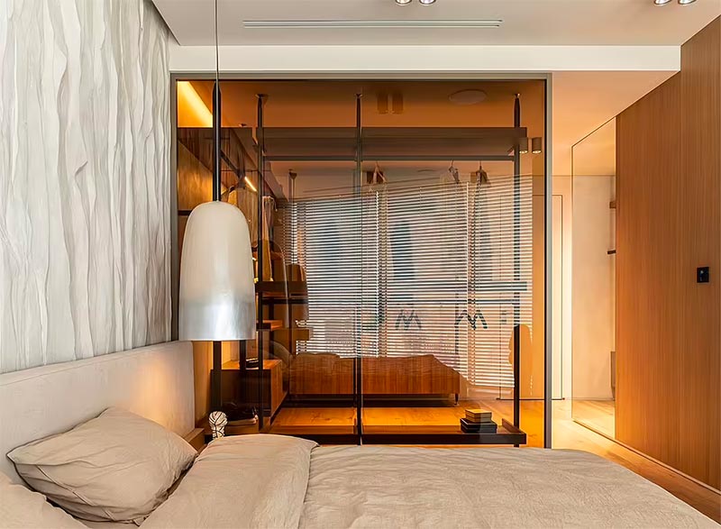 Met een glazen tussenwand, heeft Makhno Studio ervoor gezorgd dat de inloopkast ook natuurlijk licht ontvangt in deze luxe grote slaapkamer.