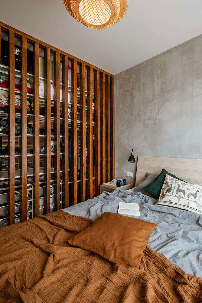 In deze slaapkamer scheidt een scheidingswand van houten latten de inloopkast van het bed