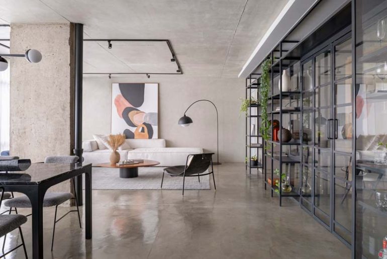 Deze stoere industriele woonkamer combineert een betonnen vloer met betonnen plafond, betonnen muren en stalen deuren met heel veel glas.