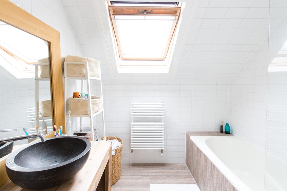 Deze kleine badkamer lijkt optisch veel groter dankzij het nieuw geplaatste dakraam in het schuine dak.