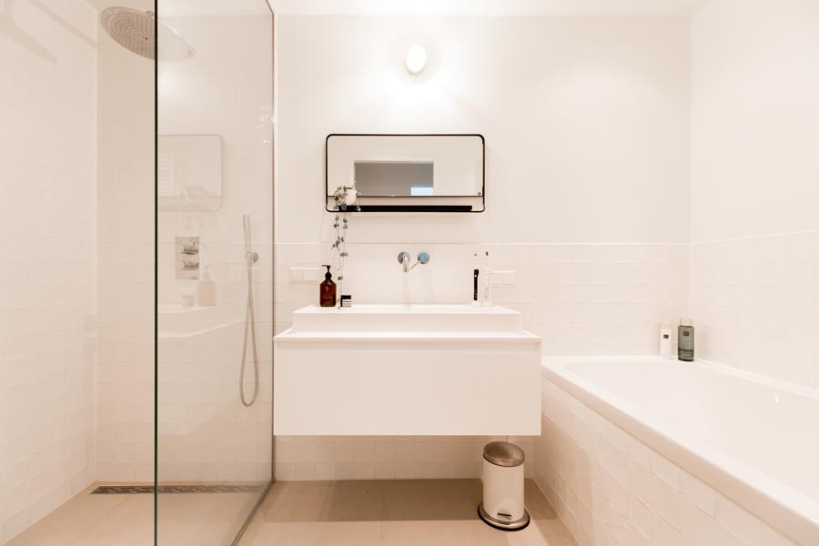 Een kleine moderne badkamer met een praktische indeling met douche en bad.