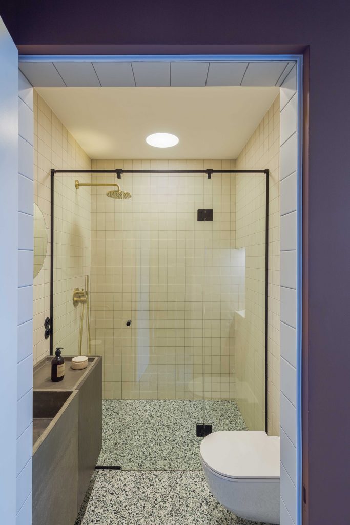 In deze kleine badkamer is er gekozen voor lichte gebroken witte wandtegels, gecombineerd met terrazzo vloertegels.