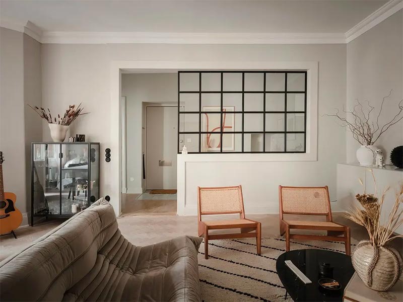 In dit appartement is er gekozen om een halve vaste muur te combineren met een glazen wand met stalen kozijnen tussen de smalle hal en de woonkamer.