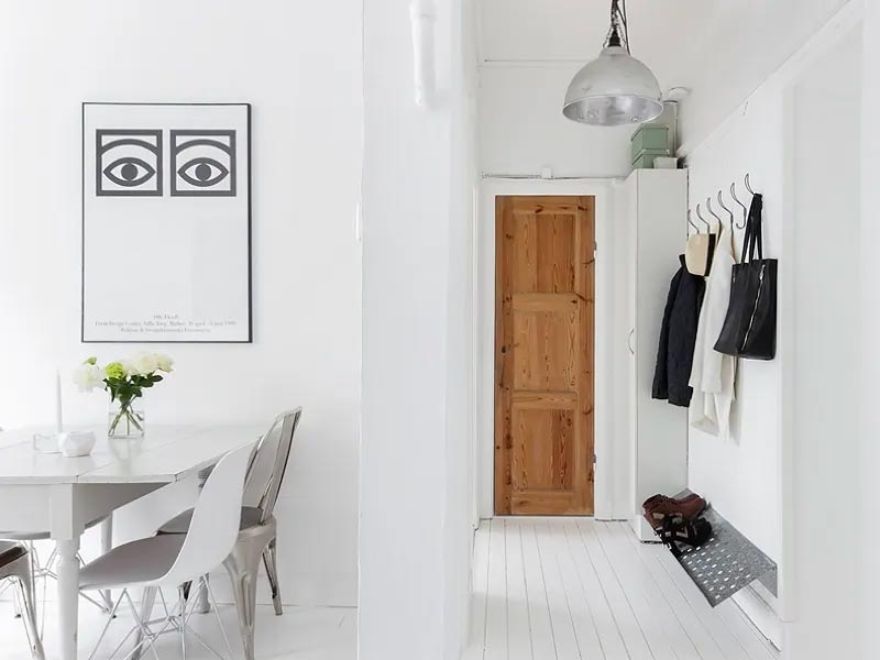 Een leuke minimalistische witte hal met een stoere schoenenrek of schoenenkast en een wandkastok.