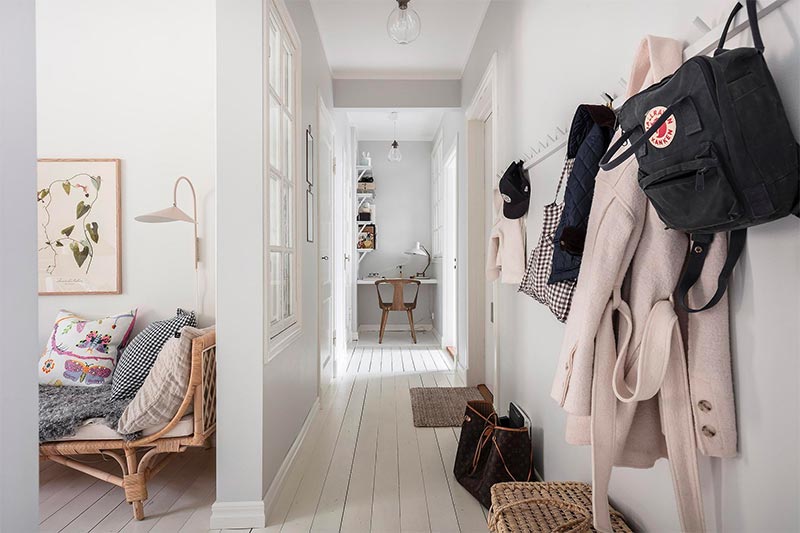 De wit geverfde houten vloer in deze smalle lange hal loopt door naar de woonkamer.