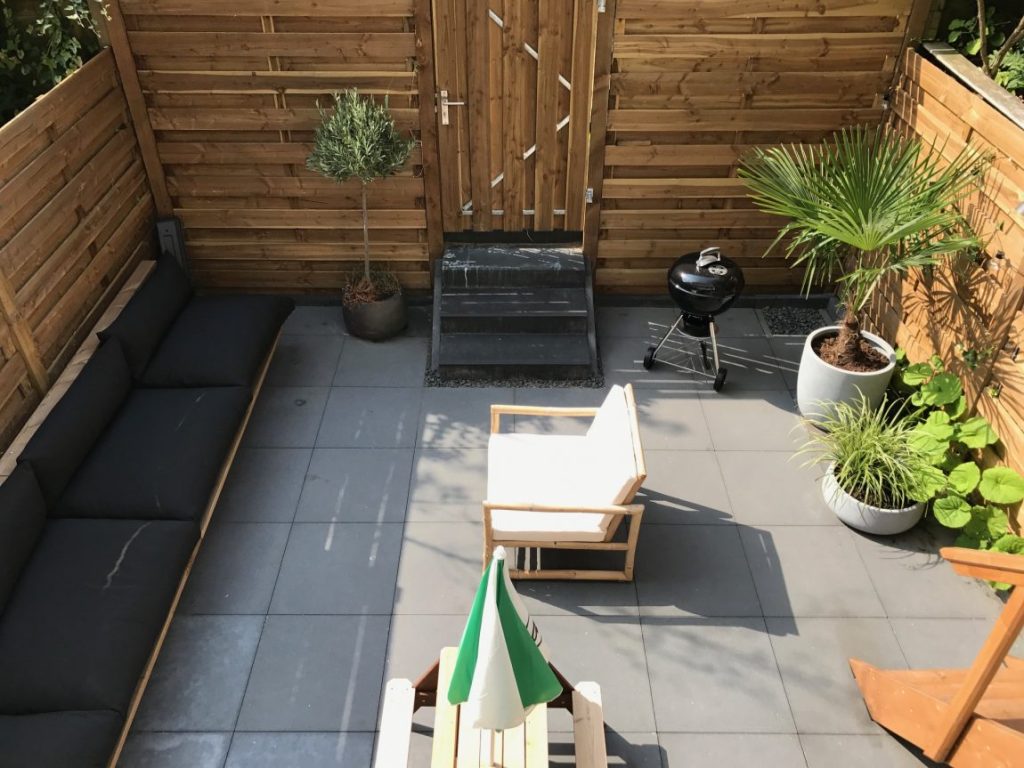Deze kleine luxe stadstuin is ingericht met neutrale kleuren zoals grijs en houttinten, gecombineerd met een vleugje groen.